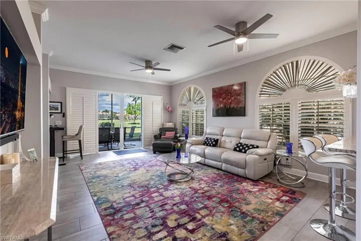 Living area with ornamental molding, a ceiling fan, and wood finished floors
