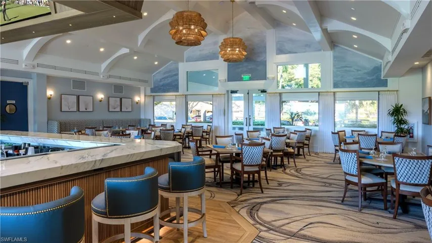 Bar area with pendant lighting, light stone counters, beam ceiling, high vaulted ceiling, and light wood-style floors