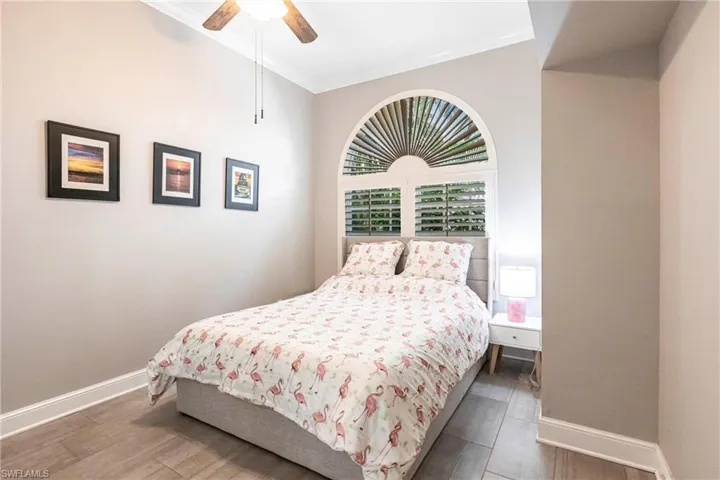 Bedroom featuring dark wood-style flooring, crown molding, and a ceiling fan