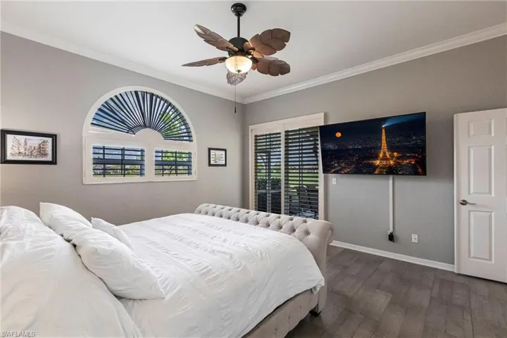 Bedroom with crown molding, dark wood-style floors, and ceiling fan