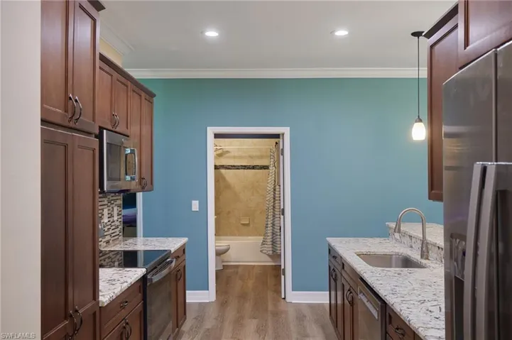 Kitchen with a sink, ornamental molding, light wood-style flooring, and stainless steel appliances