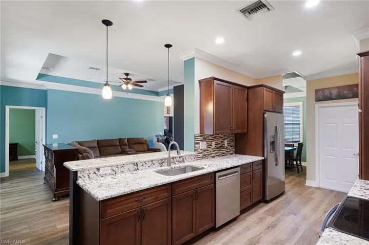 Kitchen with crown molding, ceiling fan, a sink, stainless steel appliances, and open floor plan