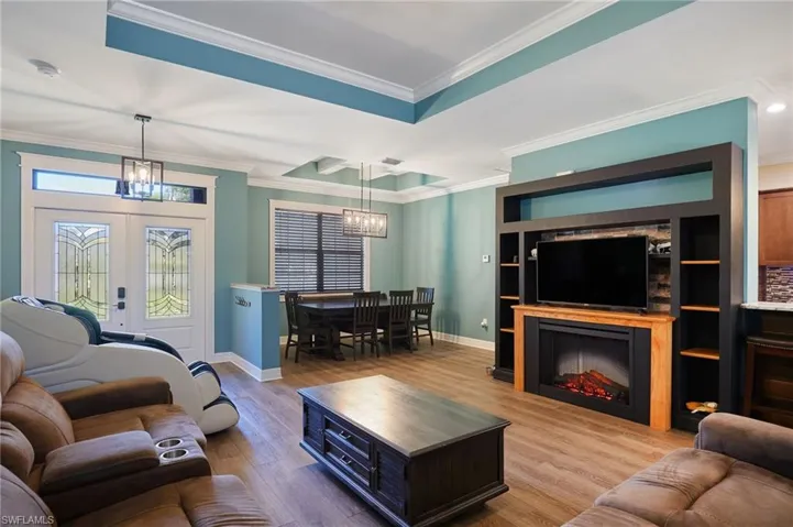 Living area with a chandelier, baseboards, and ornamental molding