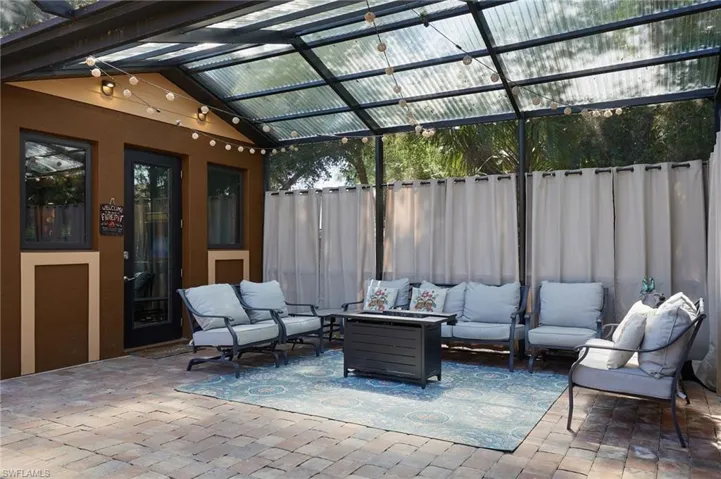 View of patio with glass enclosure, an outdoor living space, fence, and a pergola