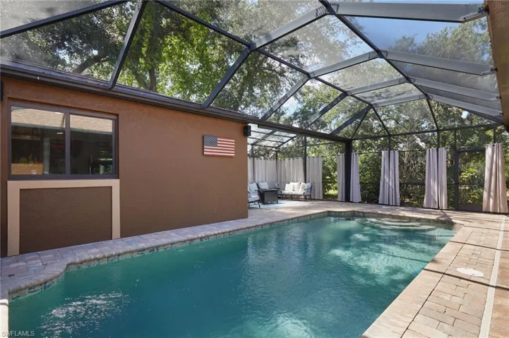 Outdoor pool with a patio, an outdoor living space, a grill, and fence
