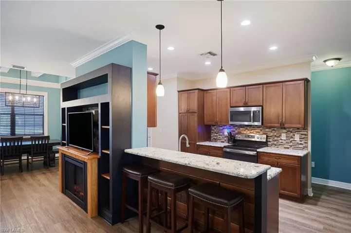 Kitchen featuring a kitchen breakfast bar, light wood-style flooring, decorative backsplash, and stainless steel appliances