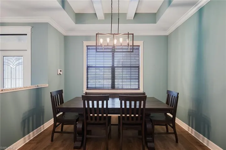 Dining room with tray ceiling and ornamental carpentry and beams