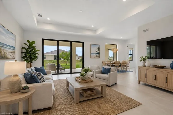 Living room featuring tray ceilings, recessed lighting, and light wood-finish flooring