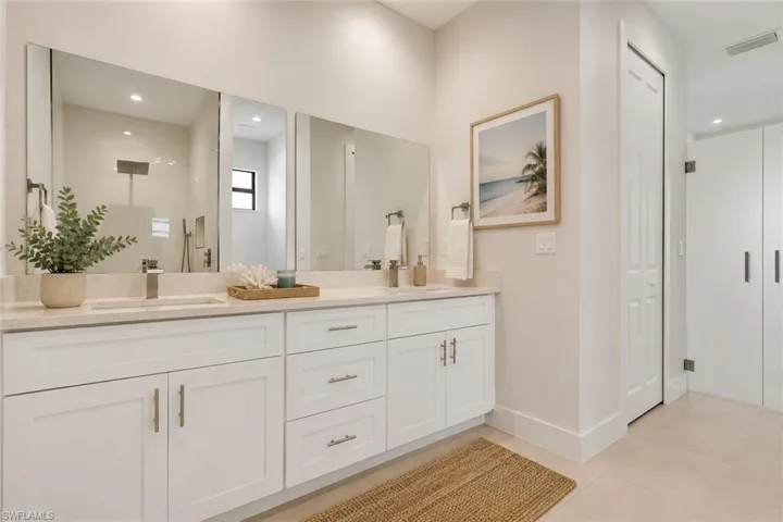 Double vanity featuring undermount sinks, stone countertops, and ample cabinet storage