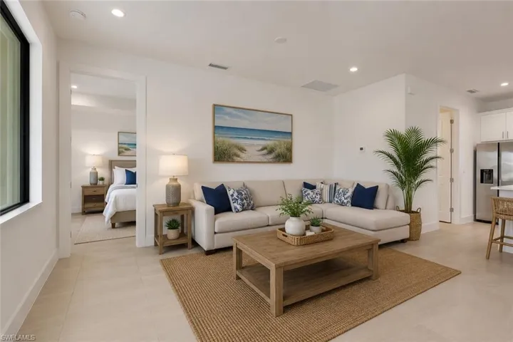 Open-concept living area featuring light-toned large format tile flooring and recessed lighting
