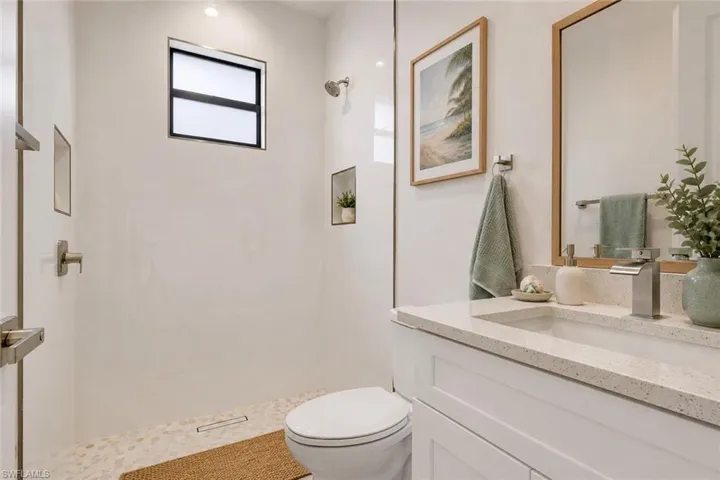 Bathroom featuring a glass-enclosed shower with pebble flooring and built-in niche