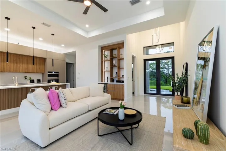 Living room featuring a tray ceiling, ceiling fan, french doors, and sink