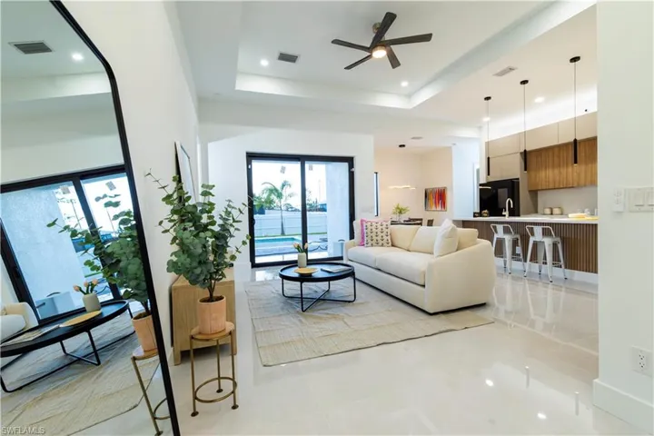 Tiled living room featuring ceiling fan and a raised ceiling