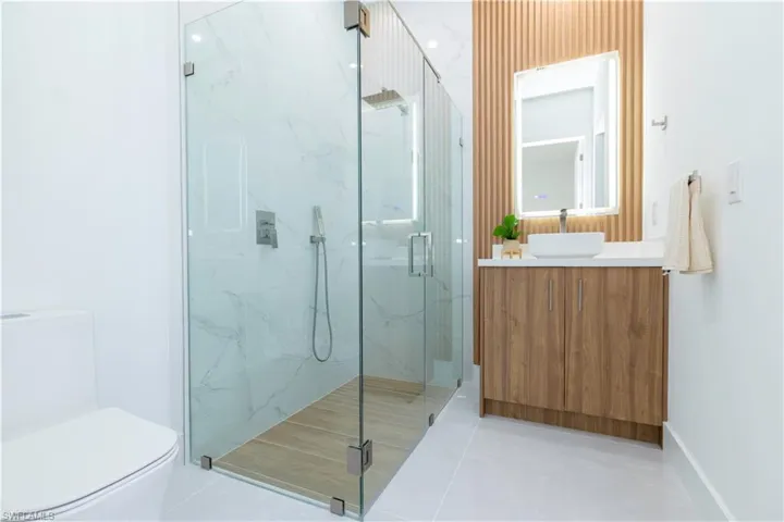 Bathroom featuring walk in shower, vanity, toilet, and tile patterned floors