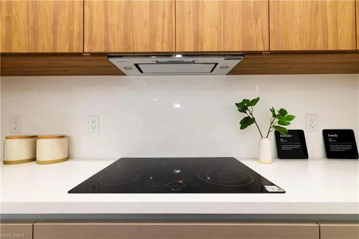 Kitchen with exhaust hood and black electric stovetop
