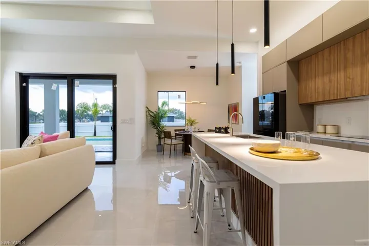 Kitchen with hanging light fixtures, a breakfast bar, black refrigerator, a center island with sink, and sink