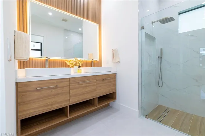 Bathroom featuring a tile shower, tile patterned floors, and vanity