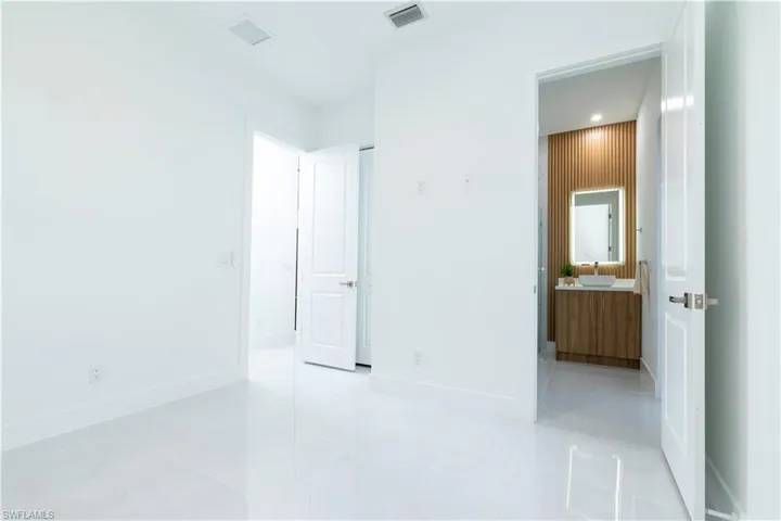 Unfurnished bedroom featuring connected bathroom and light tile patterned flooring