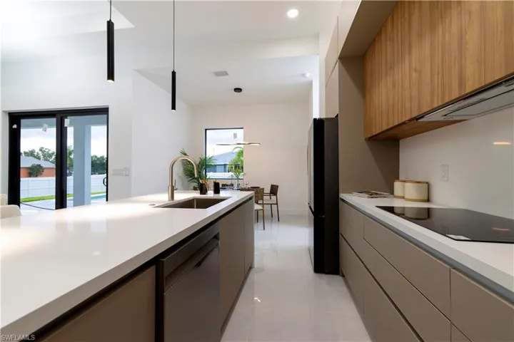 Kitchen with black appliances, hanging light fixtures, light tile patterned floors, and sink