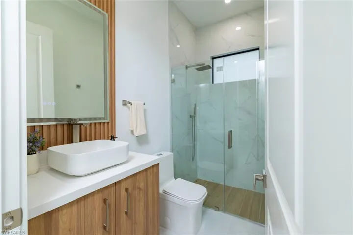 Bathroom featuring tile patterned flooring, vanity, toilet, and a shower with shower door