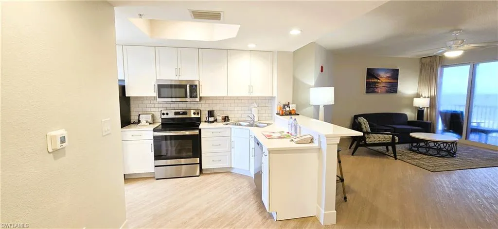 Kitchen featuring white cabinetry, light hardwood / wood-style flooring, kitchen peninsula, ceiling fan, and appliances with stainless steel finishes
