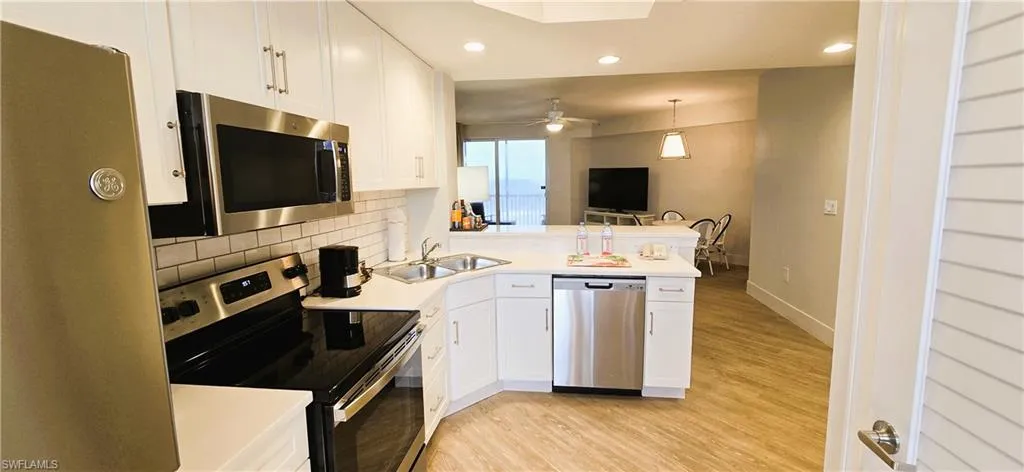 Kitchen featuring appliances with stainless steel finishes, light hardwood / wood-style flooring, sink, kitchen peninsula, and ceiling fan