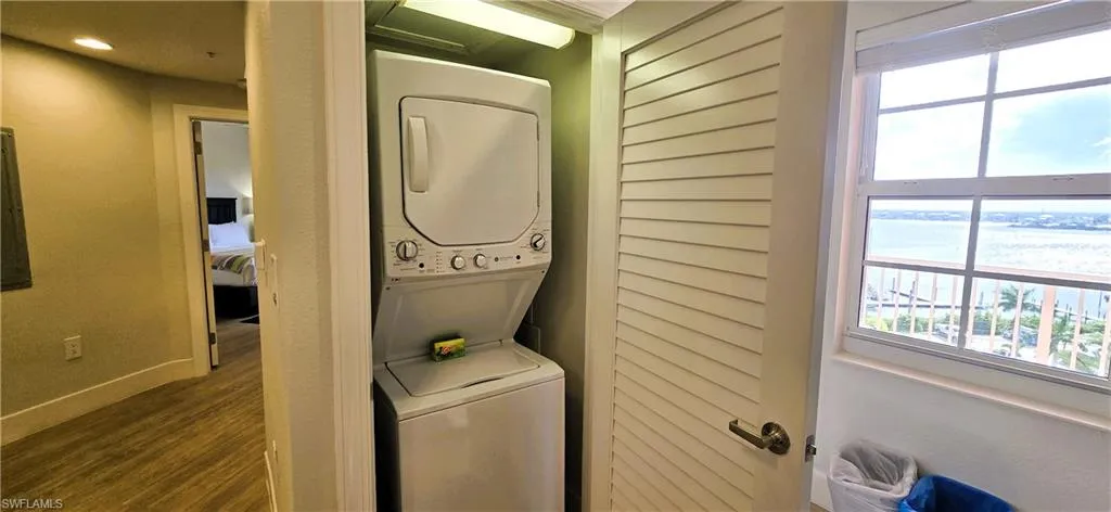 Laundry area featuring hardwood / wood-style floors and stacked washing maching and dryer