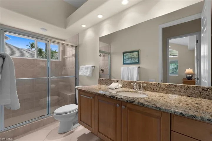 Bathroom with vanity, toilet, a shower with shower door, and plenty of natural light