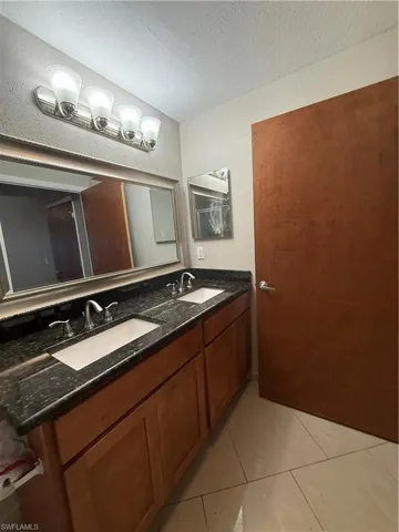 Bathroom featuring double vanity, a textured ceiling, and light tile patterned floors