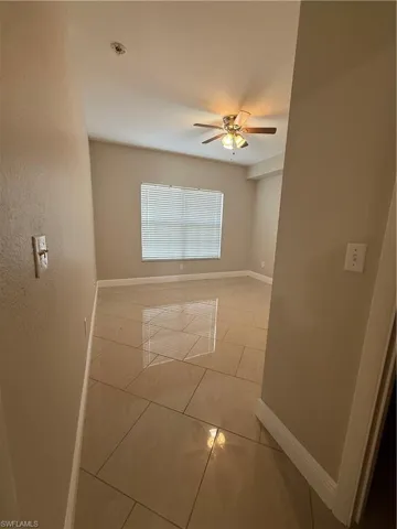 Empty room featuring a ceiling fan and light tile patterned flooring
