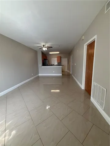 Unfurnished living room with ceiling fan and baseboards