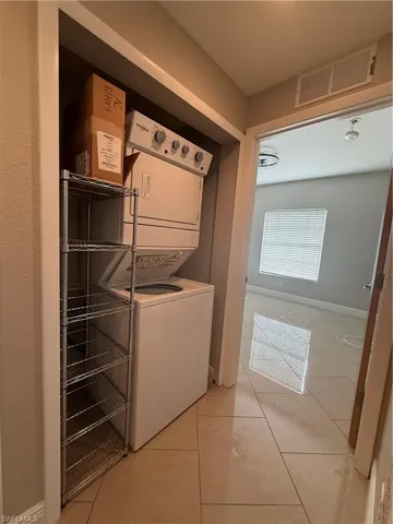 Laundry room featuring stacked washing machine and dryer and light tile patterned floors