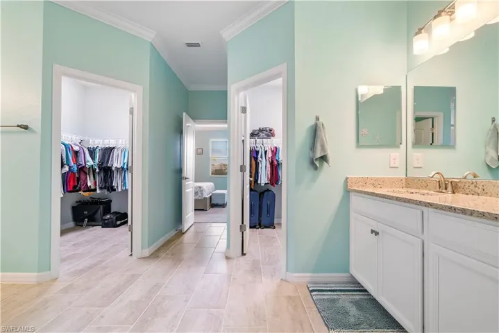 Bathroom with a spacious closet, vanity, crown molding, and ensuite bathroom
