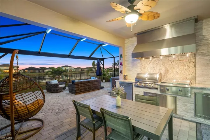 View of patio featuring a ceiling fan, outdoor lounge area, an outdoor kitchen, glass enclosure, and a sunroom