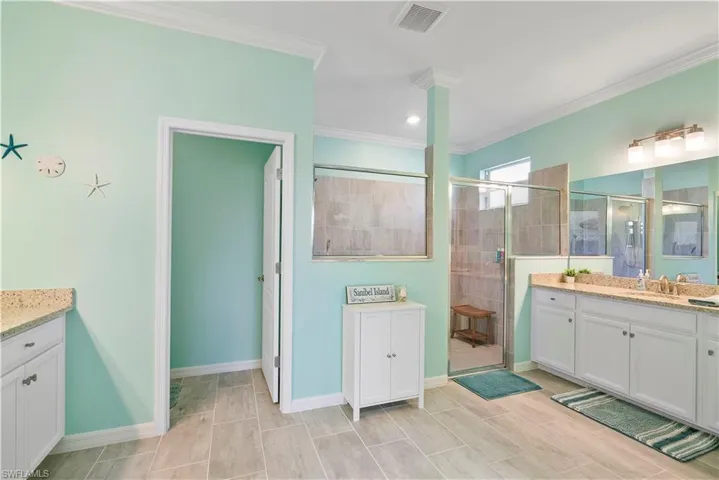 Bathroom with vanity, a stall shower, and ornamental molding