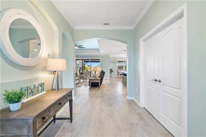 Corridor featuring arched walkways, crown molding, and light wood finished floors