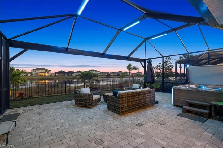 Patio terrace at dusk featuring a lanai, a sunroom, a patio area, a hot tub, and a residential view