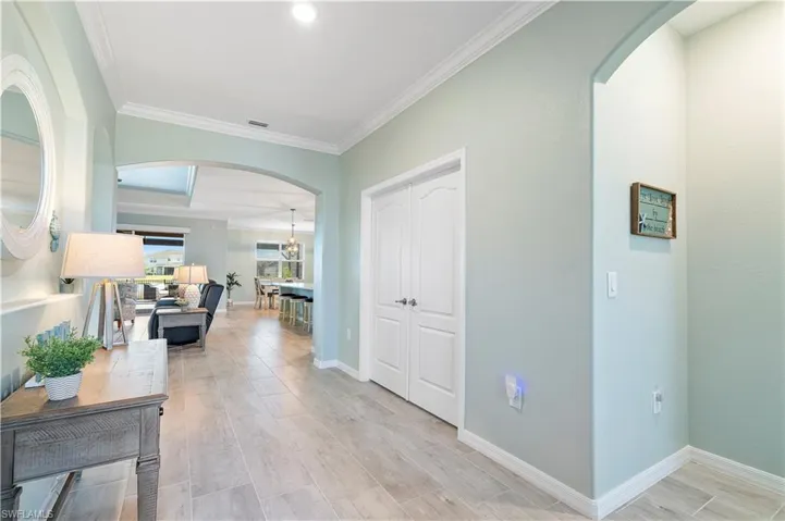 Corridor with arched walkways, crown molding, and wood tiled floors