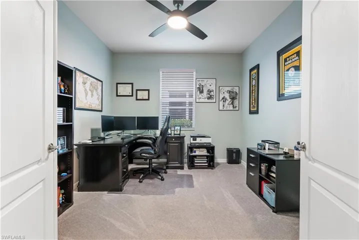 Office with light carpet and ceiling fan