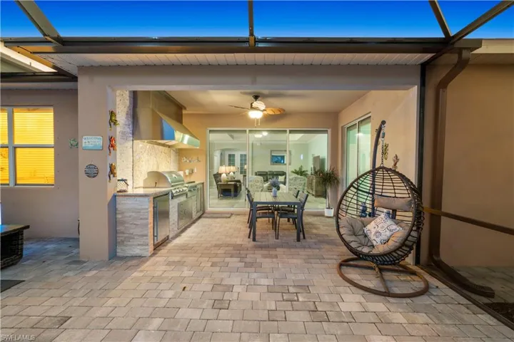 View of patio with an outdoor kitchen / dining area, glass enclosure, and ceiling fan