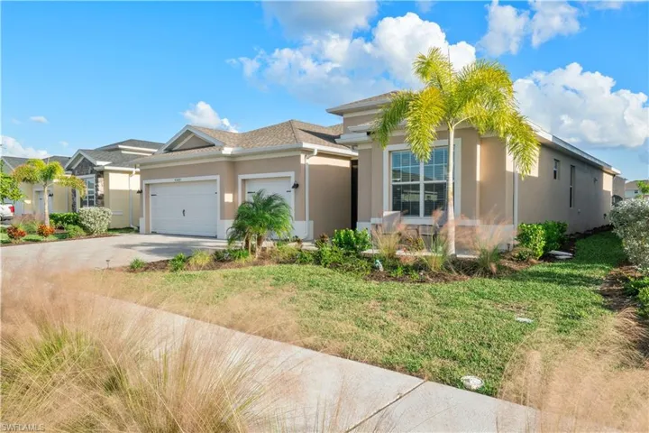 Ranch-style house featuring a garage, driveway, stucco siding, and a front lawn