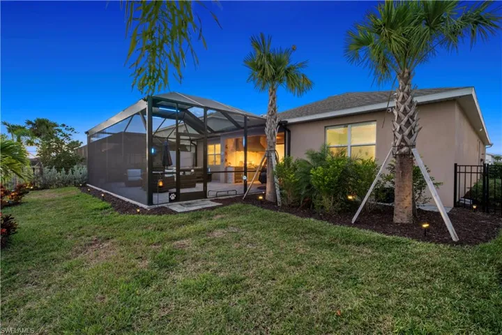 Back of property with a sunroom, stucco siding, glass enclosure, and a patio
