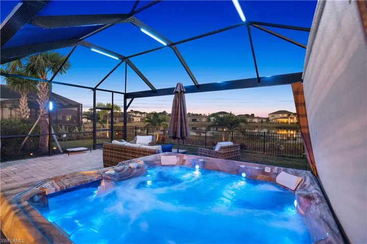 View of pool featuring a sunroom, glass enclosure, a fenced backyard, a hot tub, and a swimming pool