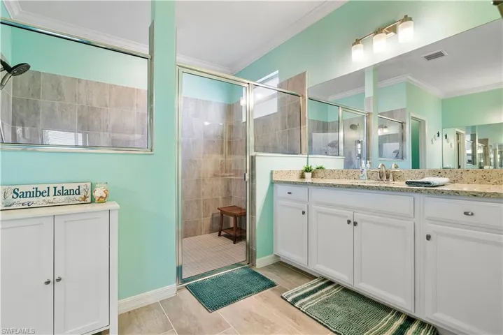 Bathroom with vanity, a stall shower, and ornamental molding