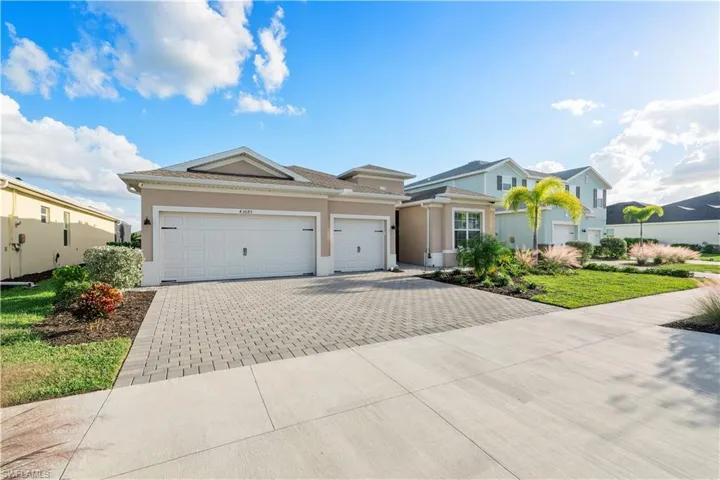 View of front facade with decorative driveway, stucco siding, and an attached garage