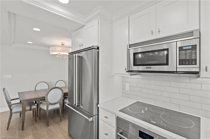 Kitchen featuring crown molding, white cabinets, stainless steel appliances, tasteful backsplash, and recessed lighting