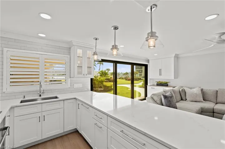 Kitchen featuring crown molding, white cabinetry, light stone counters, decorative backsplash, and light wood finished floors