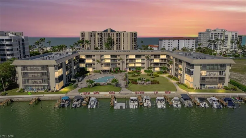 Aerial view at dusk of a water view, a view of apartment building / complex, and view of marina