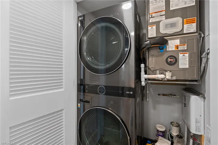 Washroom featuring stacked washing machine and dryer and heating unit
