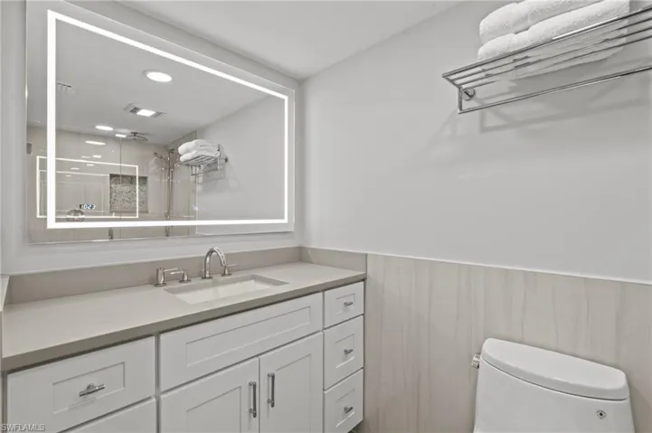 Bathroom with vanity, a shower, a wainscoted wall, and recessed lighting